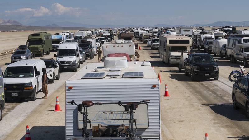 Vehicles line up to leave the Burning Man festival in Black Rock Desert, Nev., Tuesday, Sept....